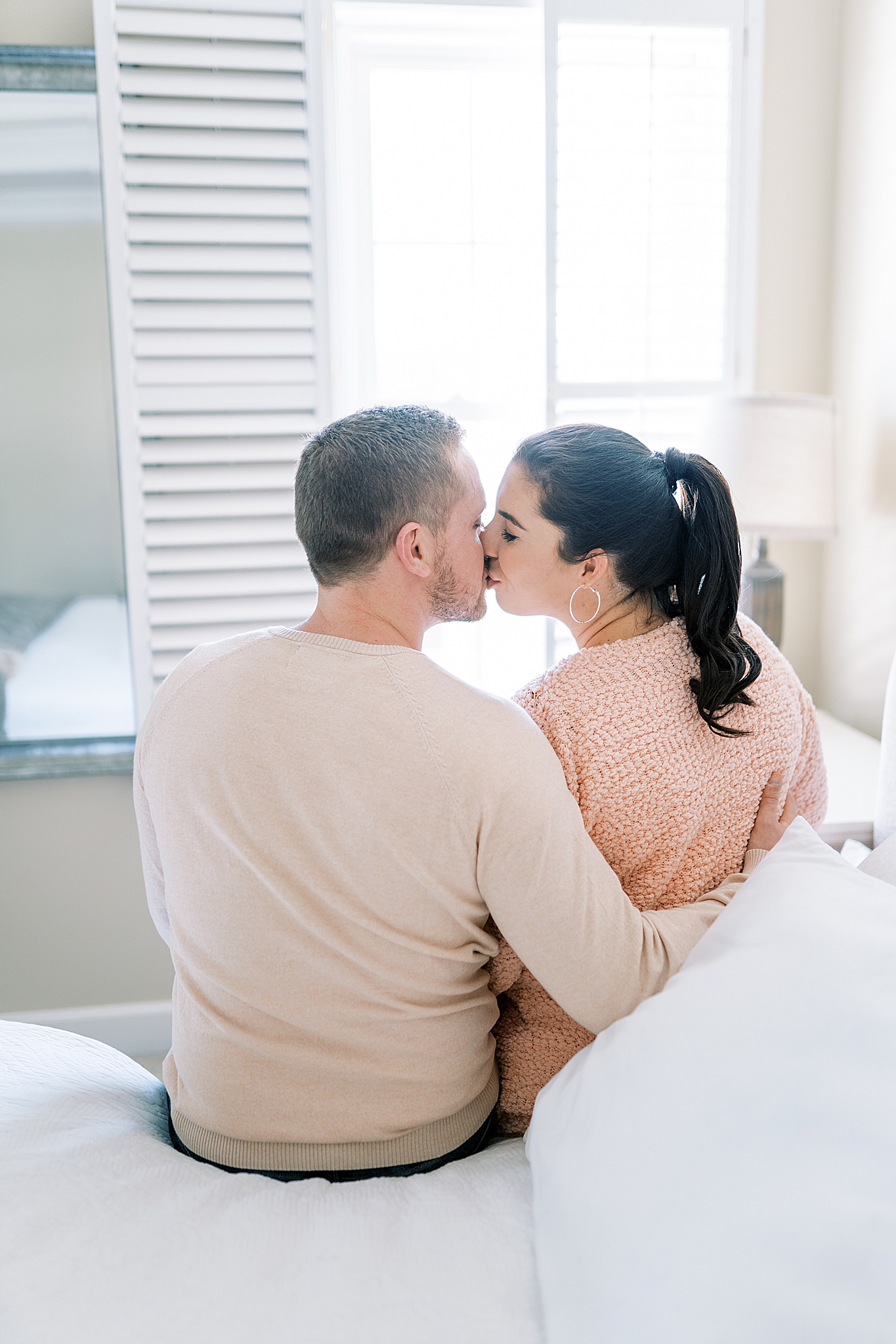 parents kiss sitting on bed during Murfreesboro lifestyle maternity session