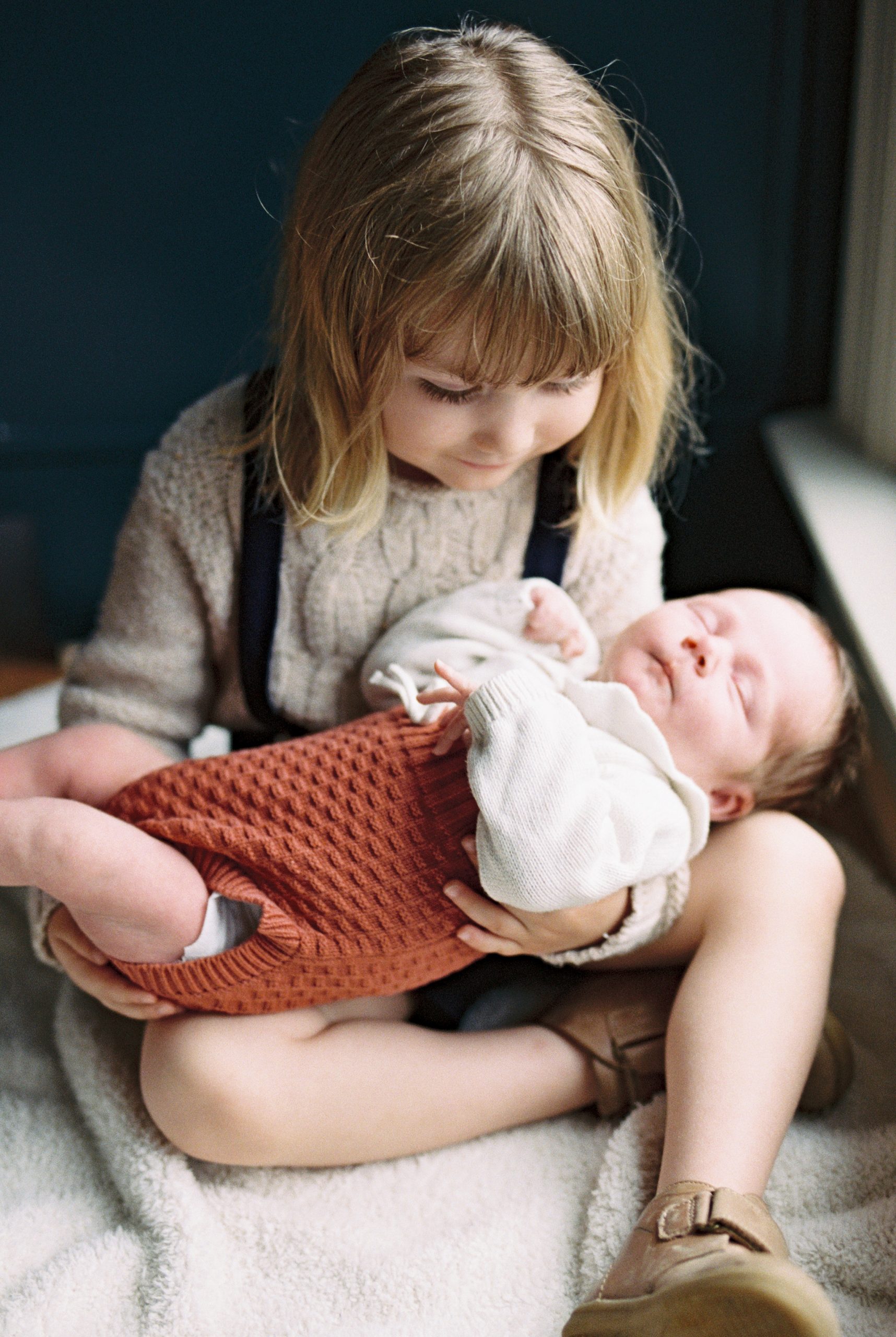 big brother holds new baby girl during Nashville lifestyle newborn portrait session