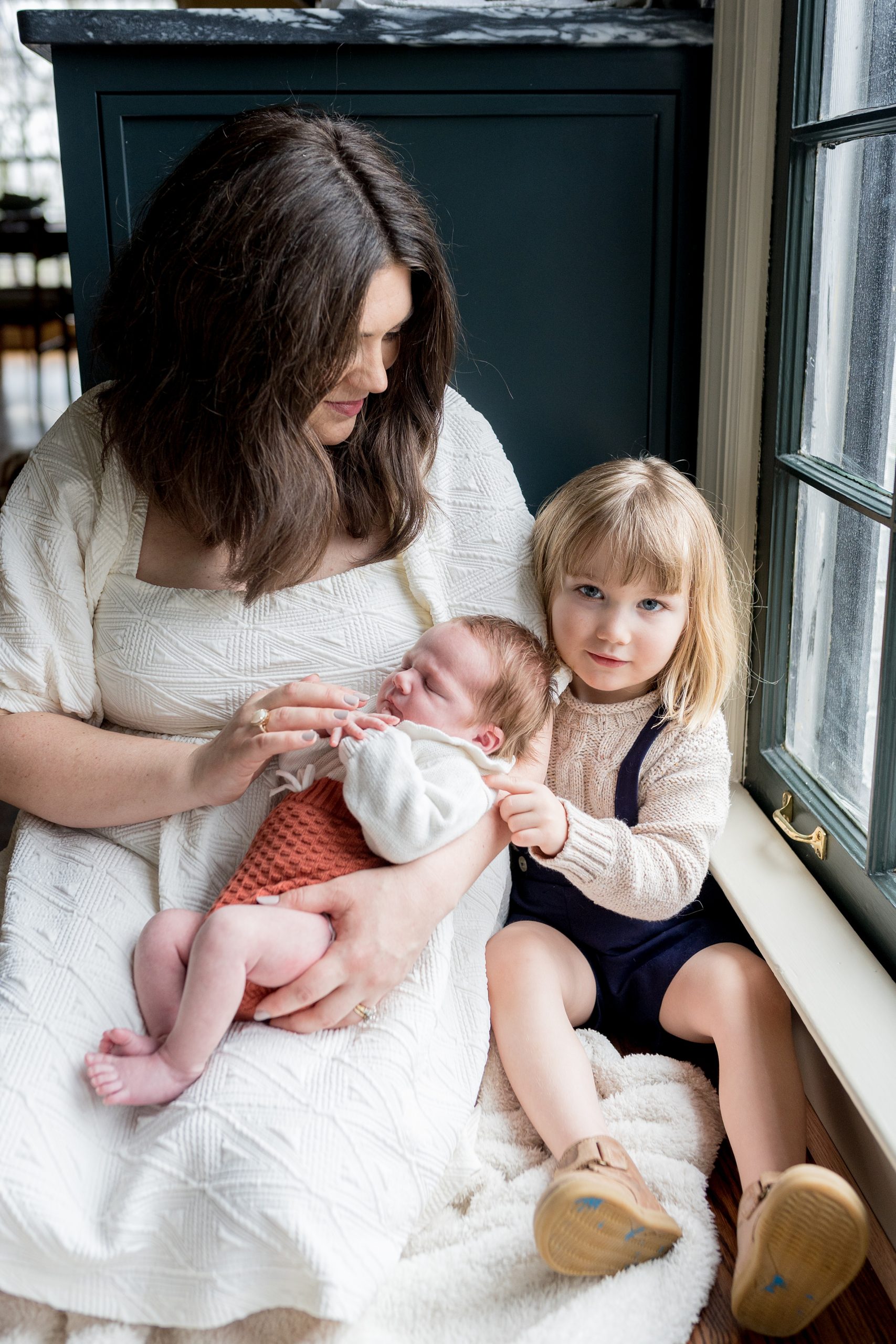 mom snuggles with two babies during Nashville lifestyle newborn portrait session