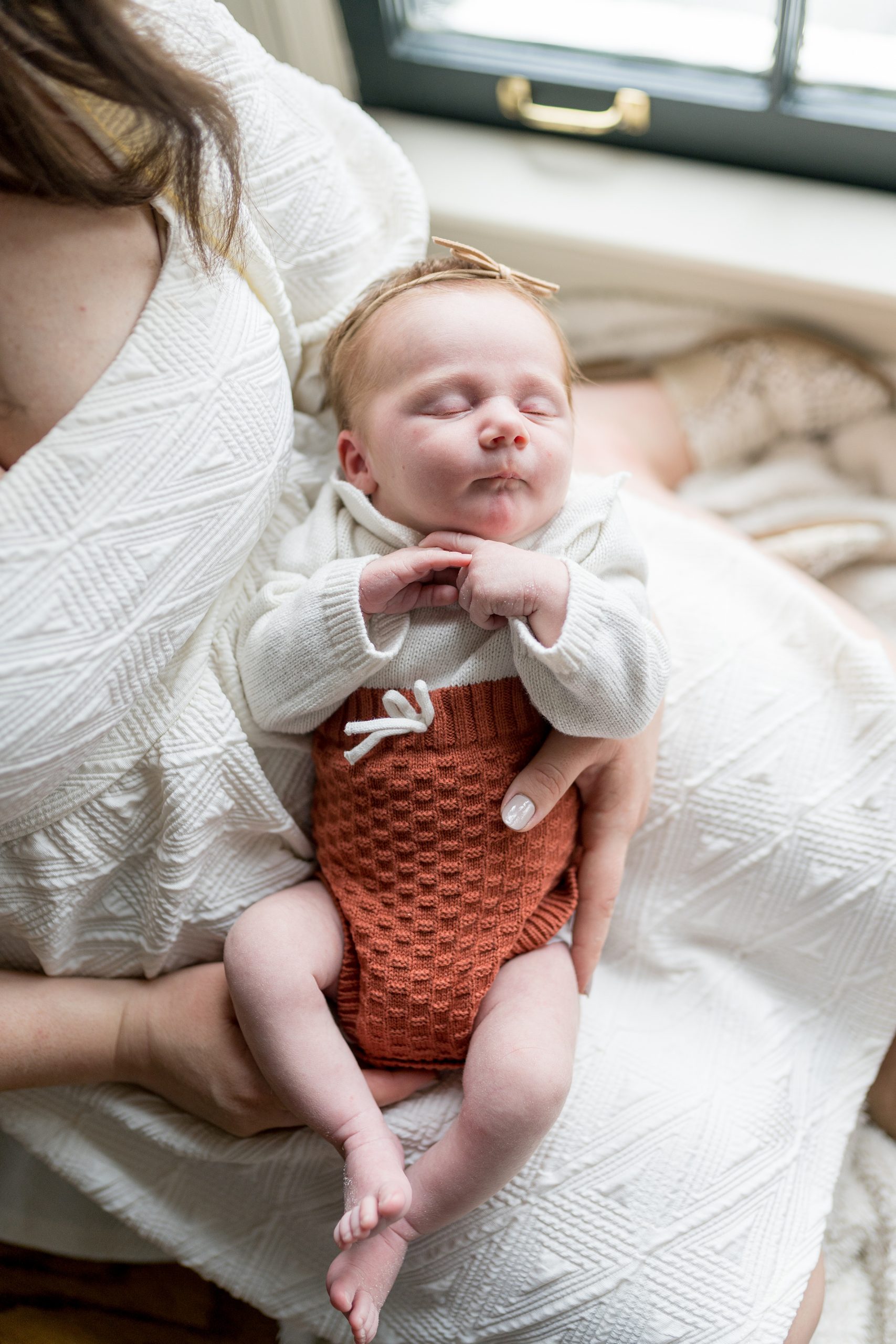 daughter lays in mom's lap during Nashville lifestyle newborn portrait session