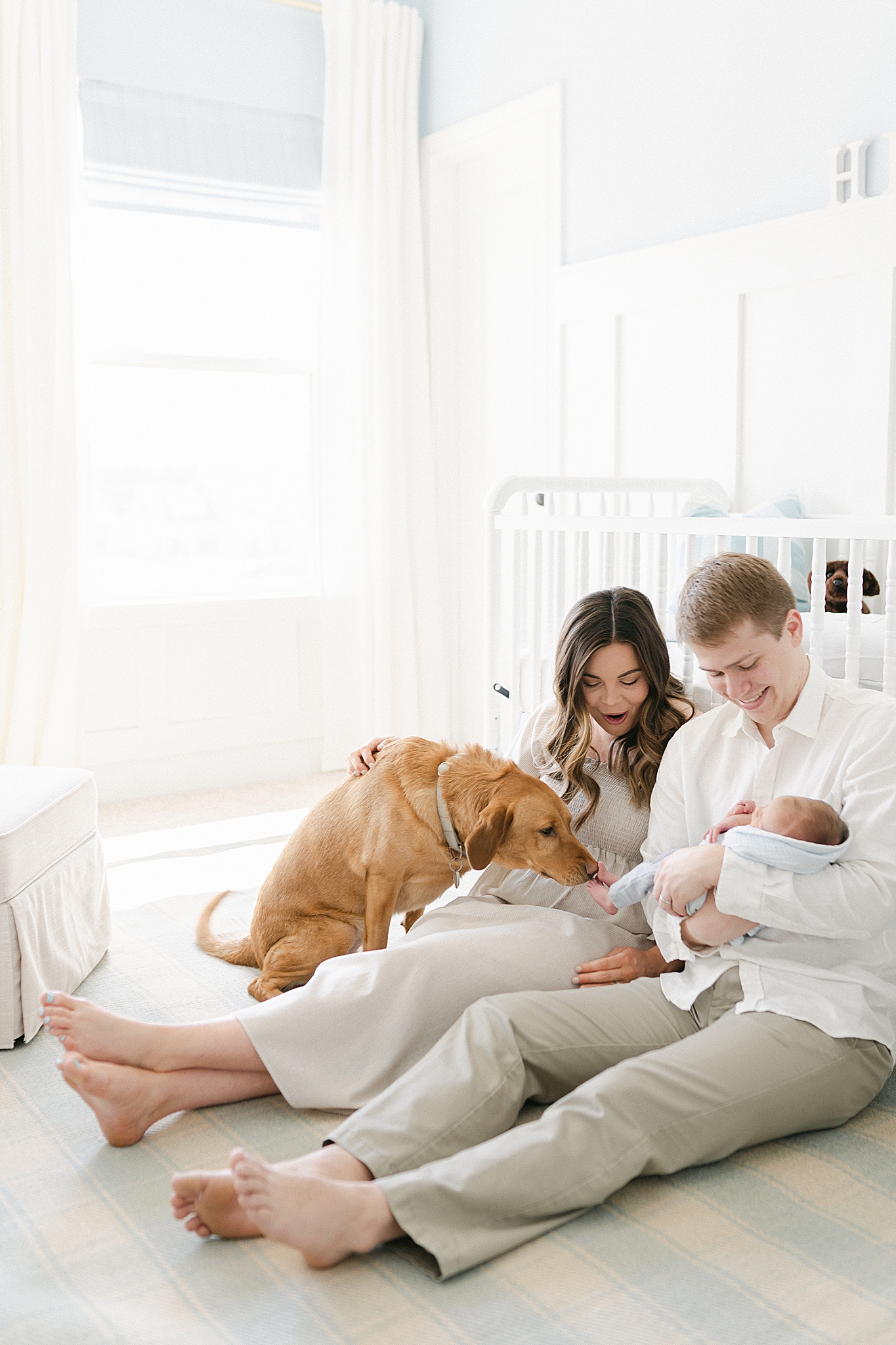 parents sit on floor with newborn son and dog
