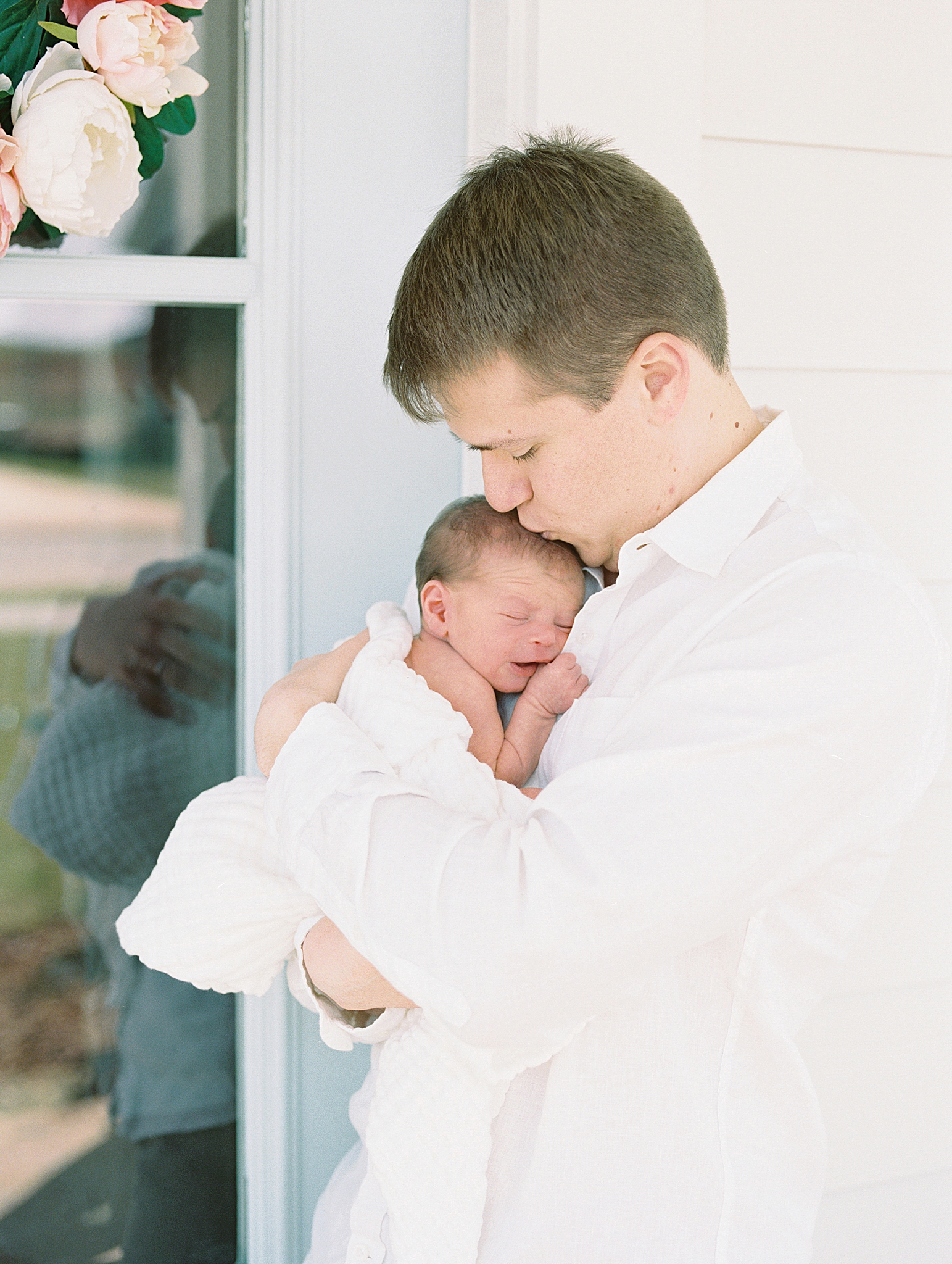 dad holds baby outside front door during at home newborn portraits
