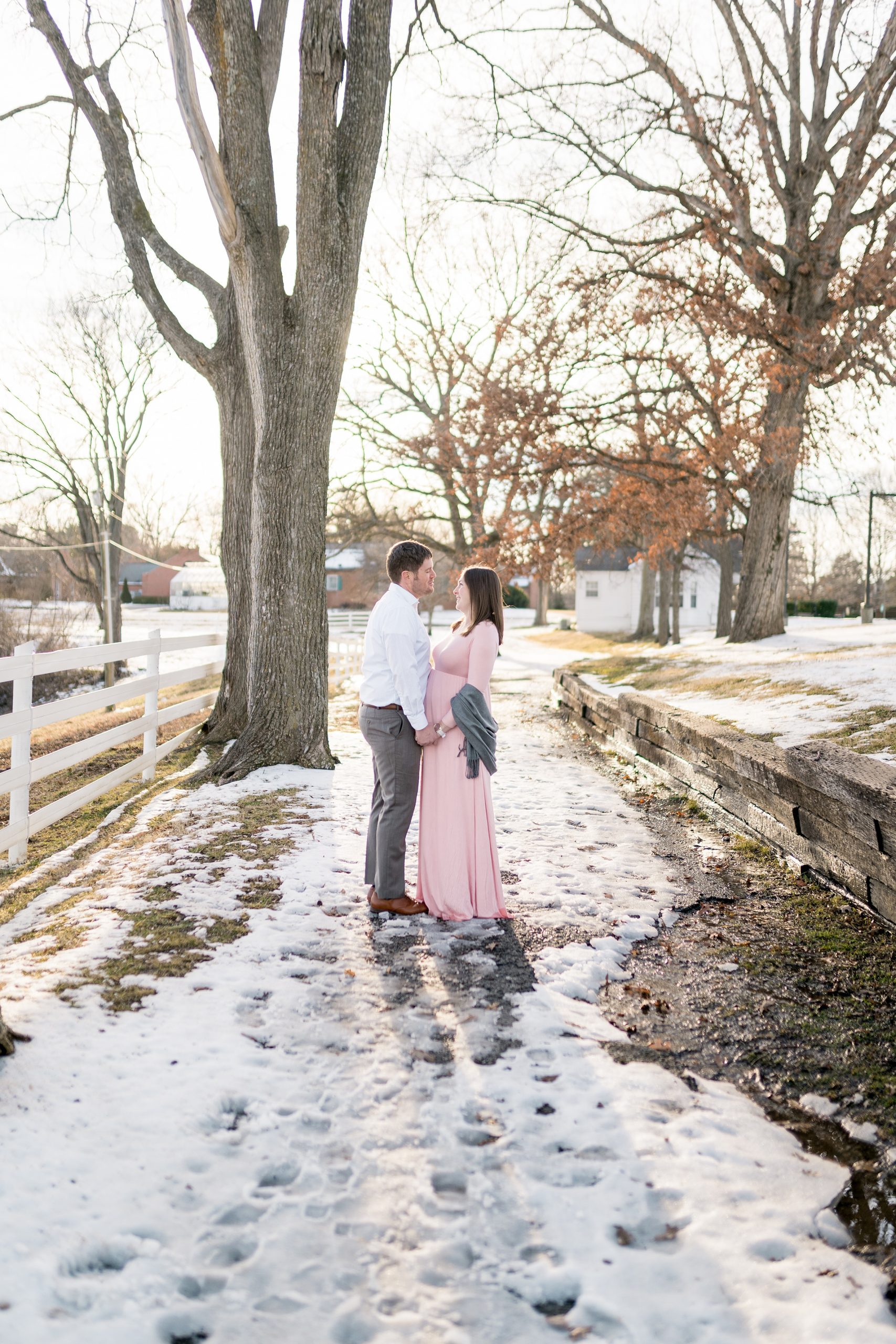 parents smile on snow covered pathway photographed by Nashville maternity photographer