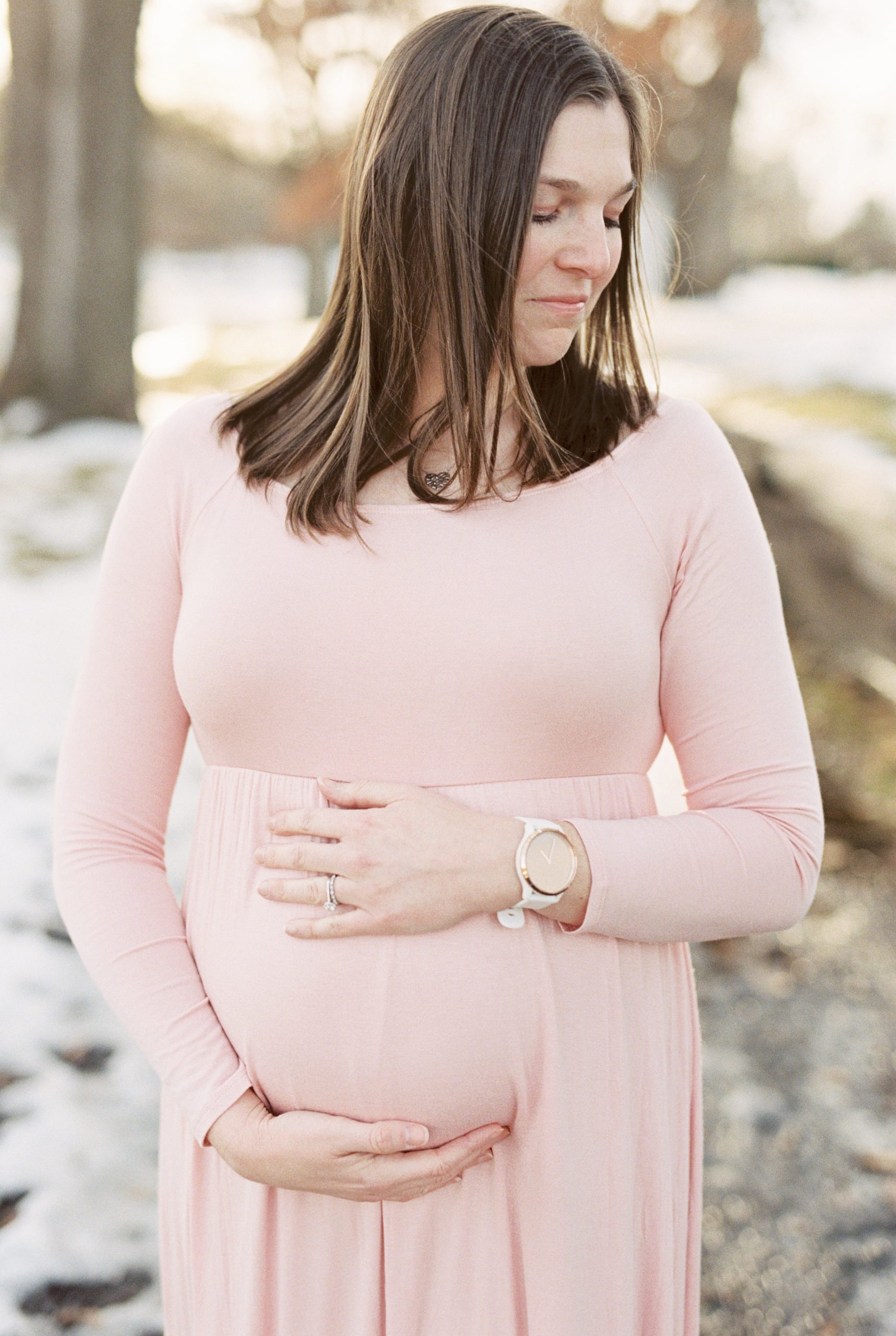 mama in pink gown holds belly during maternity portraits