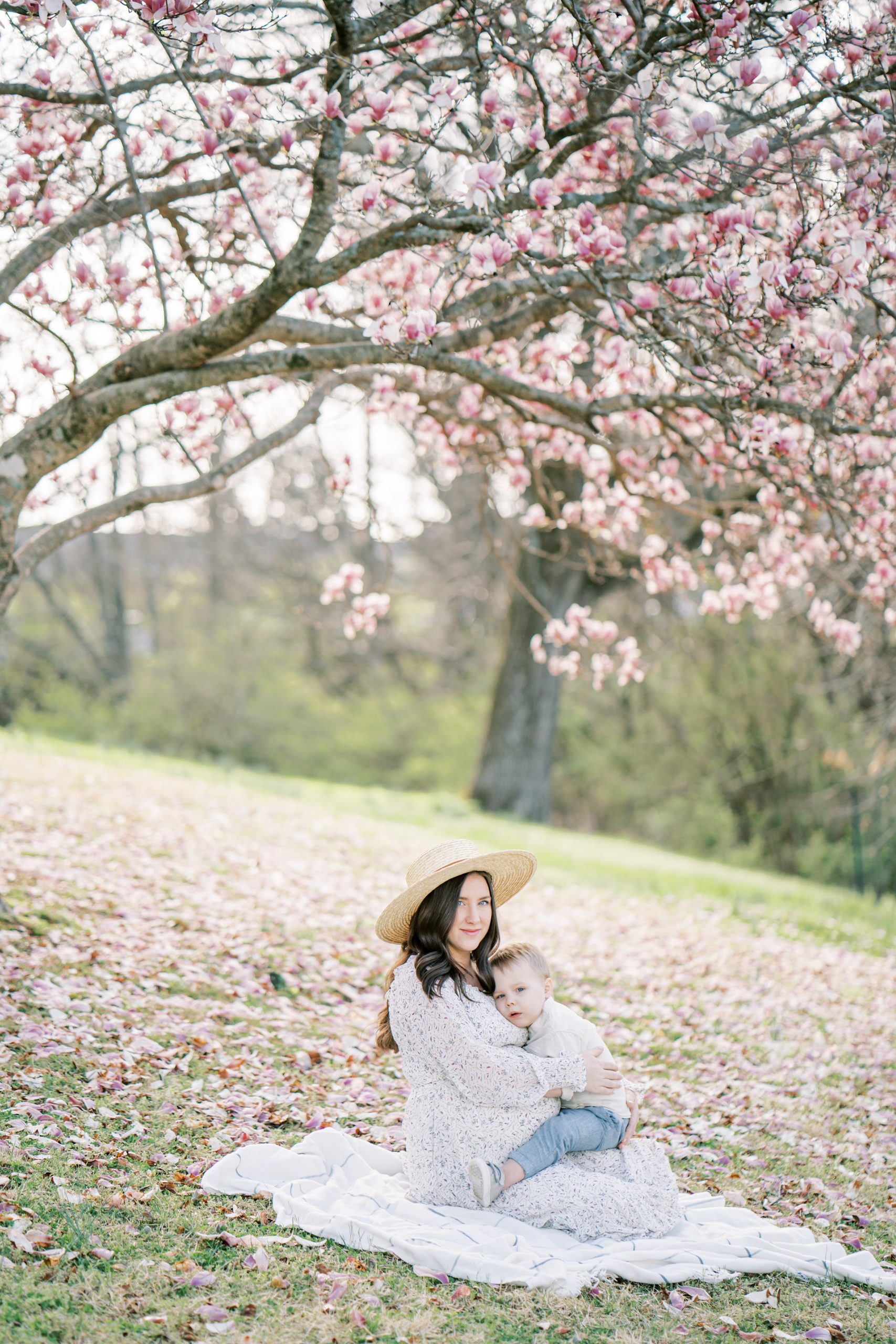 mom poses with son during Ellington Agricultural Center Maternity Session under cherry blossom tree