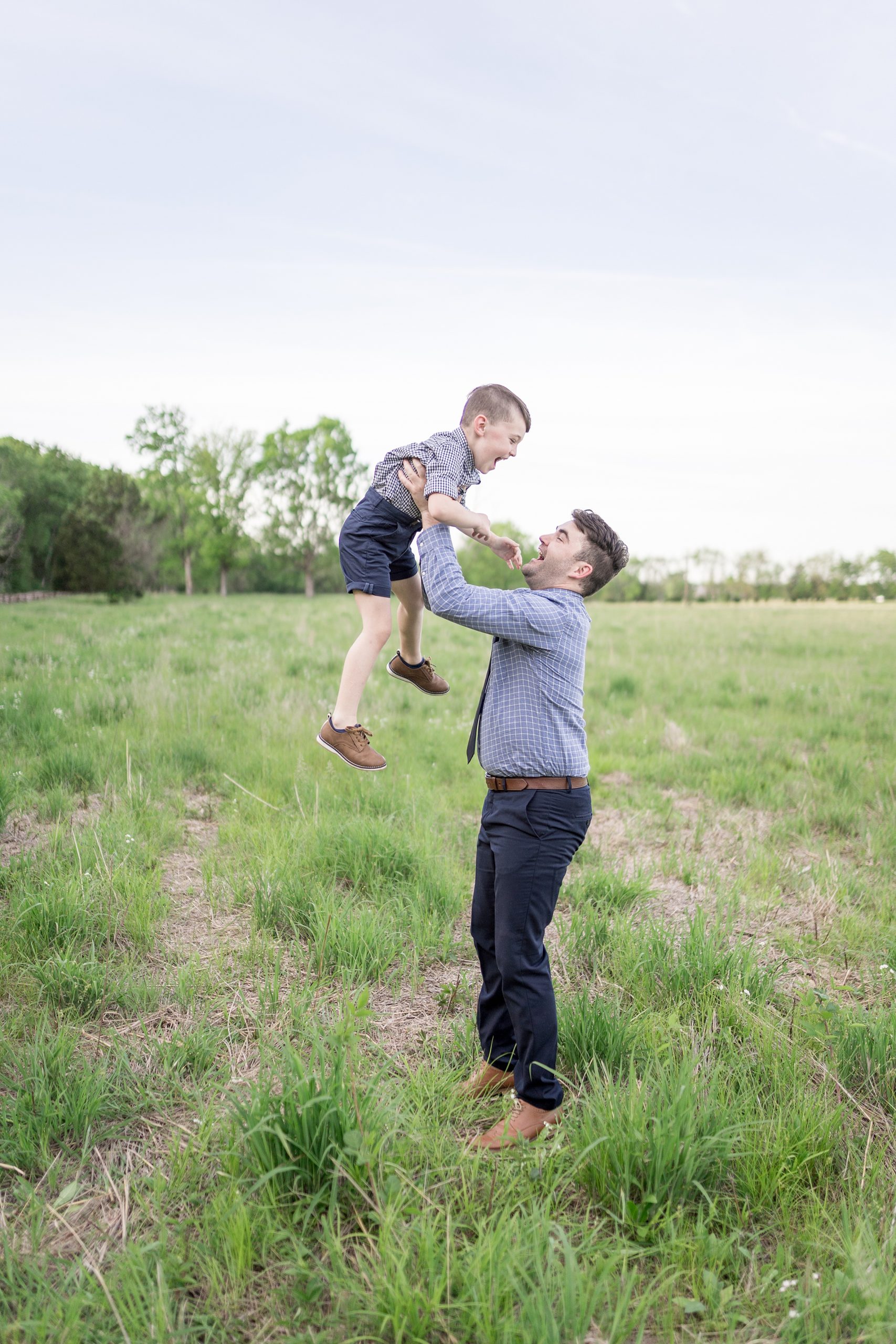 Dad throws son in air as they both laugh during family portraits