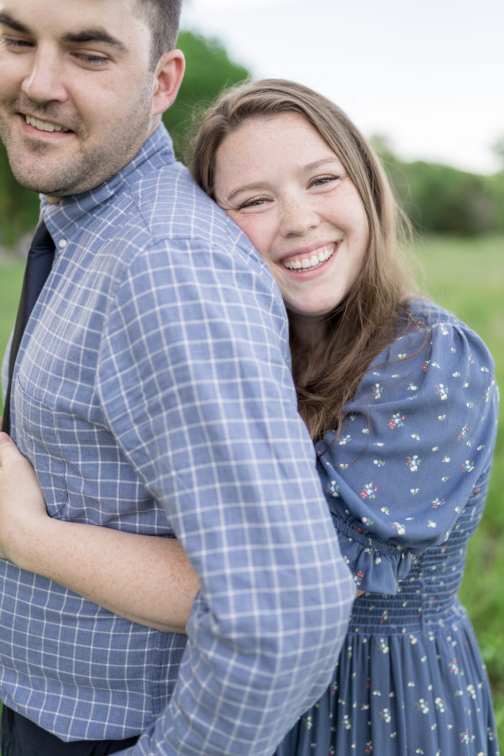 wife hugs husband from behind during family portraits