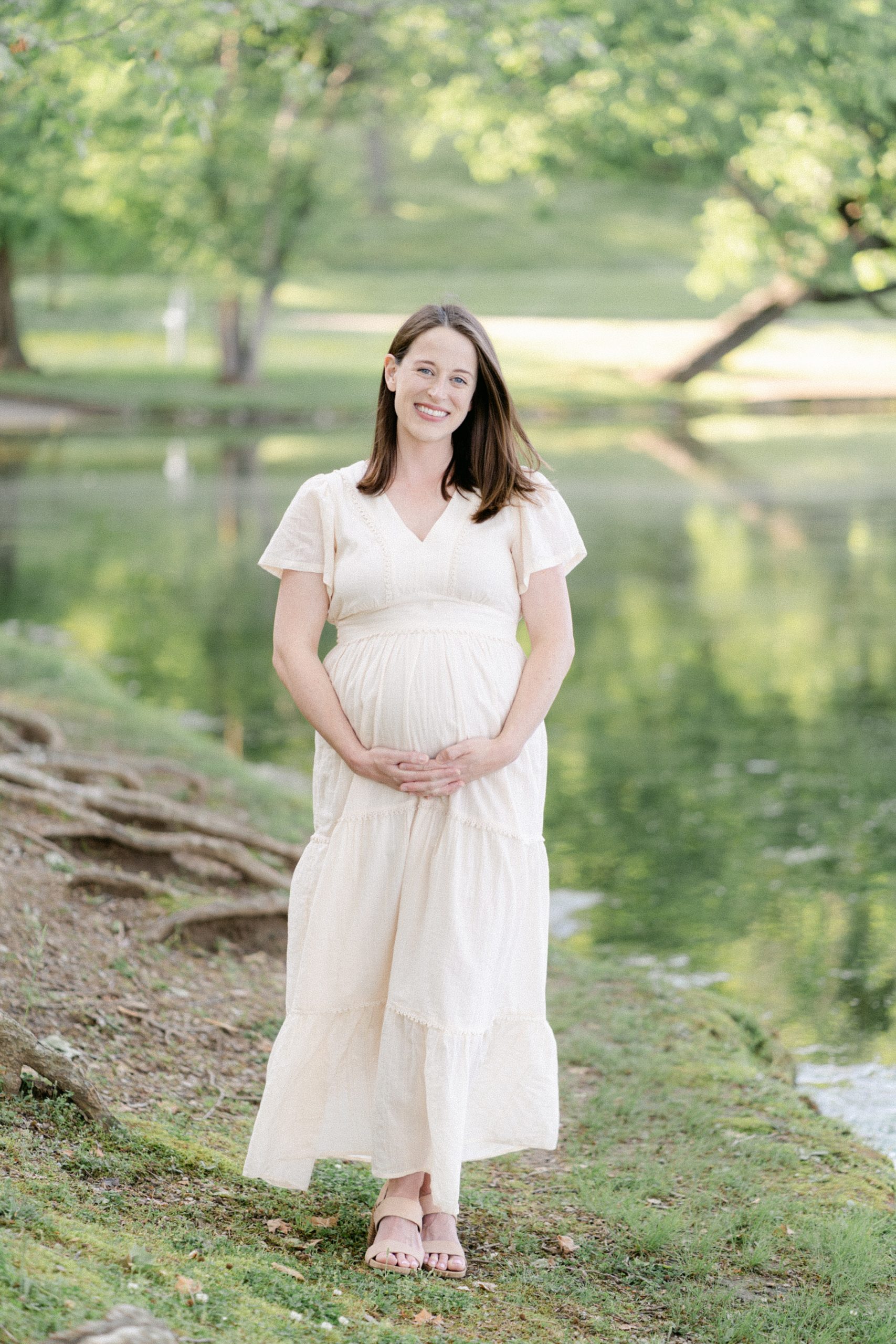 mama holds baby belly by pond for TN Maternity portraits