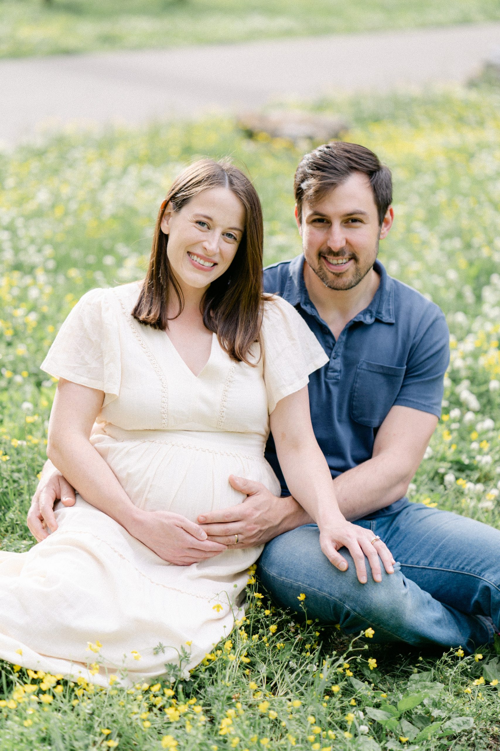 mom and dad sit in field for maternity portraits