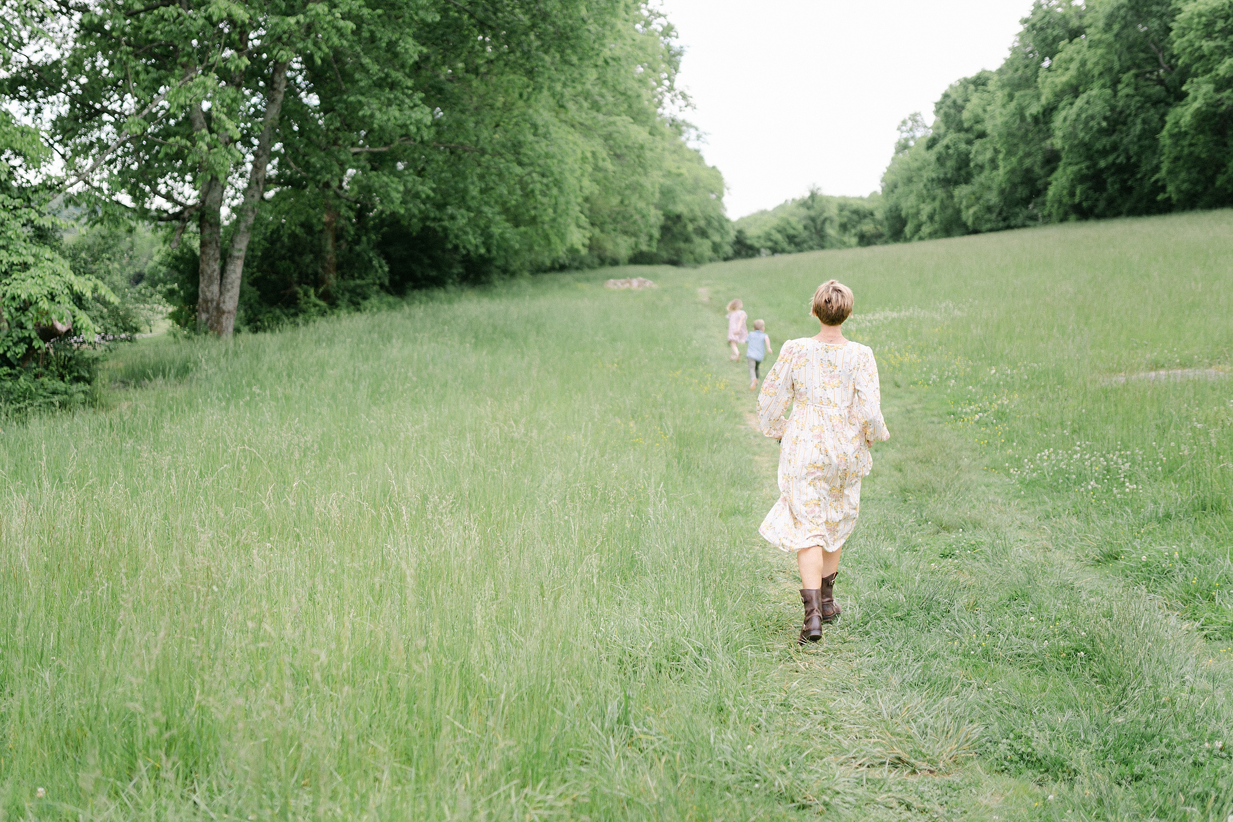 mom chases kids in field during springtime photos