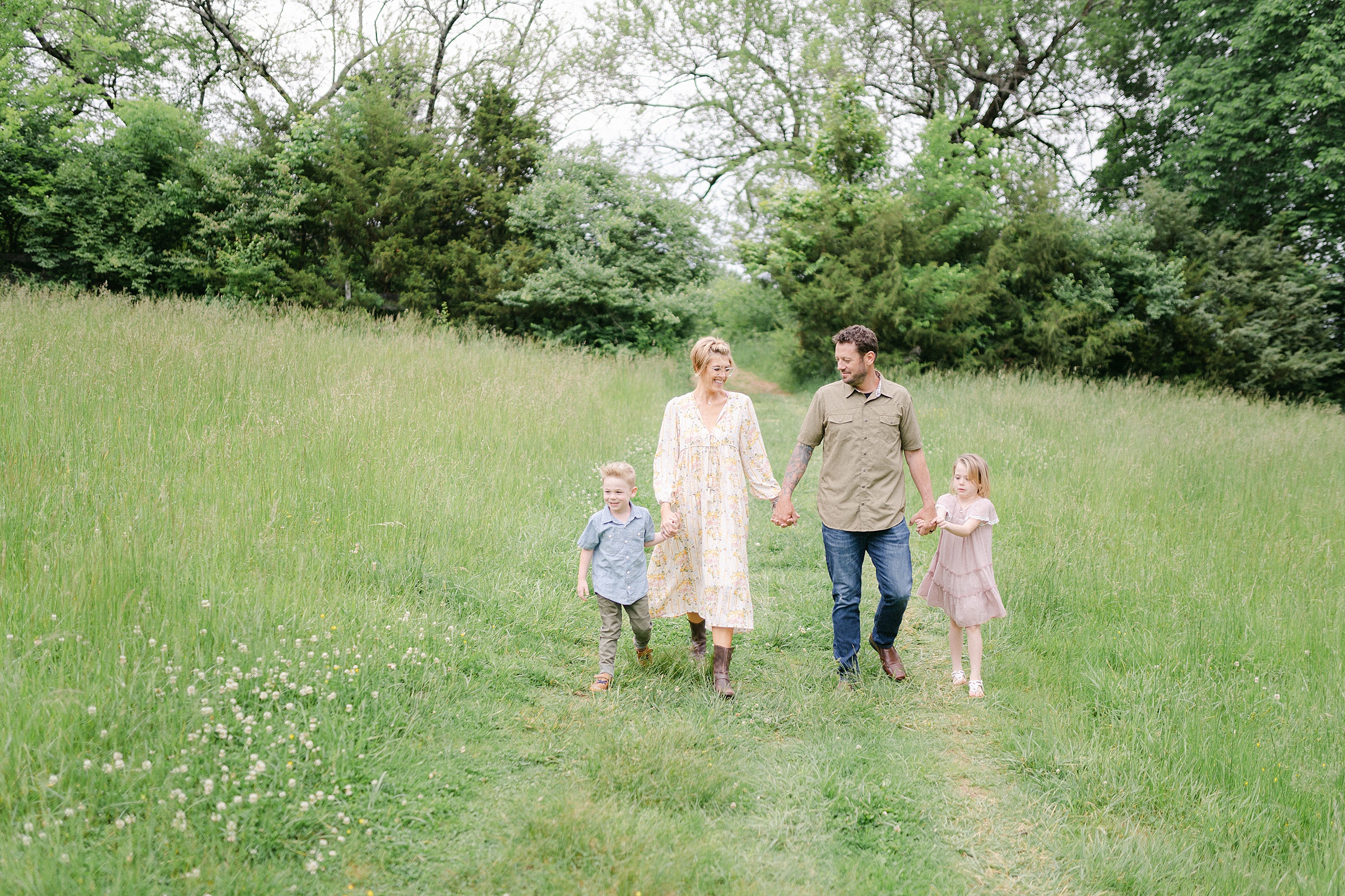 family holds hands and walks in field during Brentwood family photos