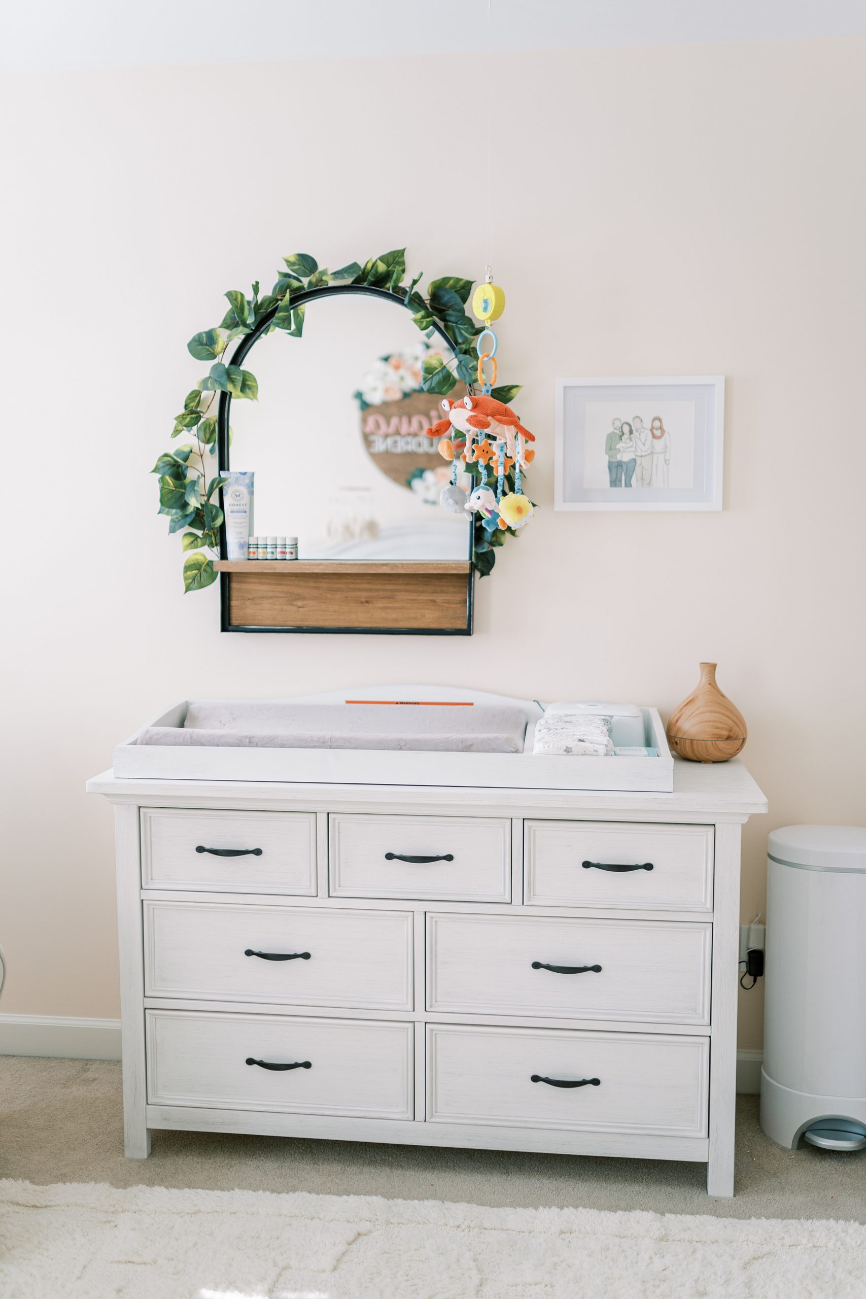 baby girl nursery spotlight- details of nursery featuring mirror and white dresser-changing table
