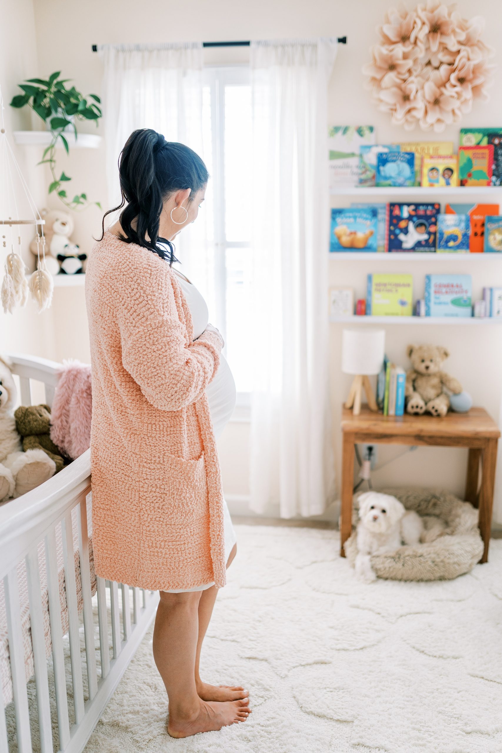 Mama in baby girls light and airy nursery during maternity photos