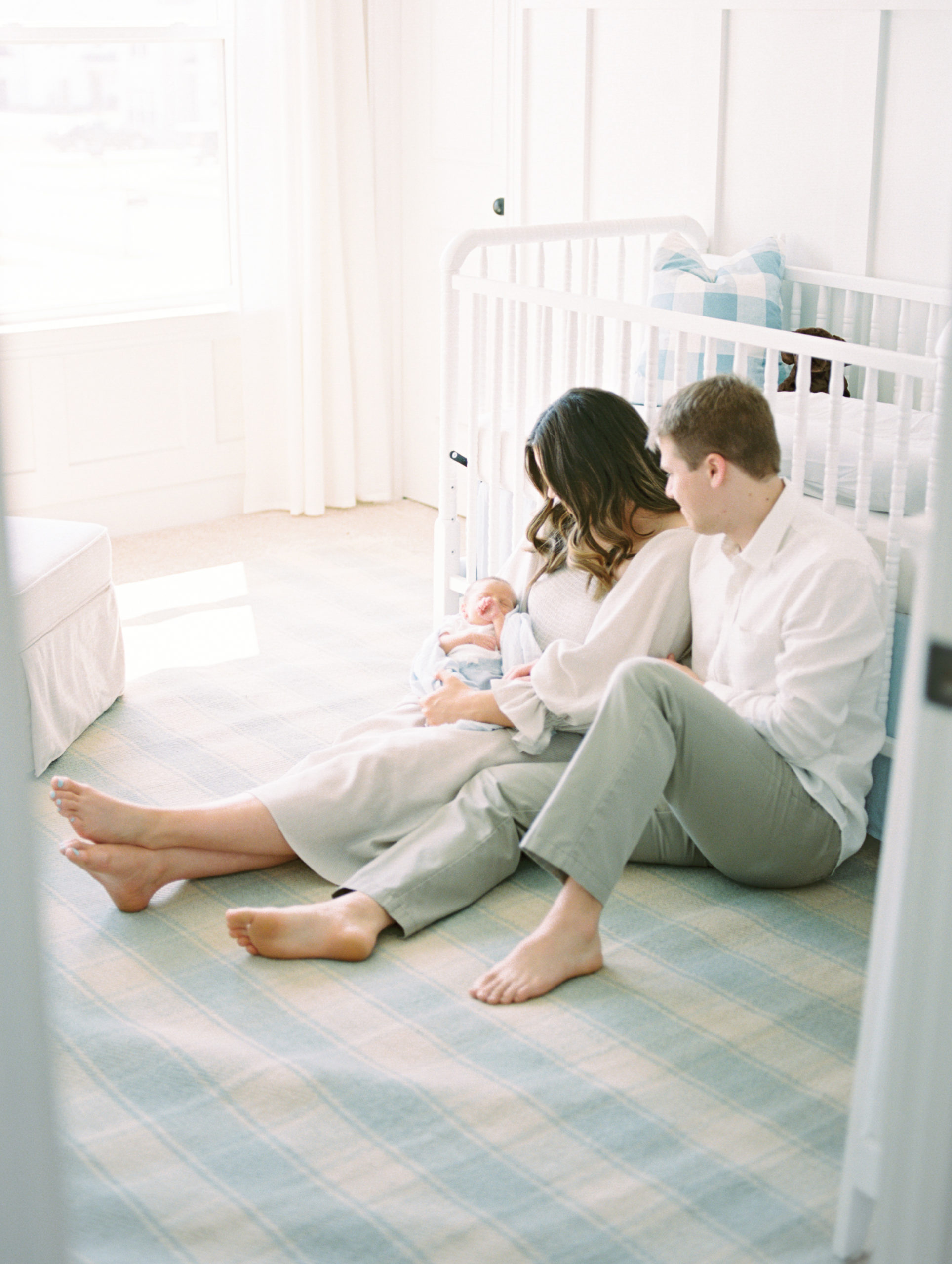 Family cuddles newborn son in light + airy nursery
