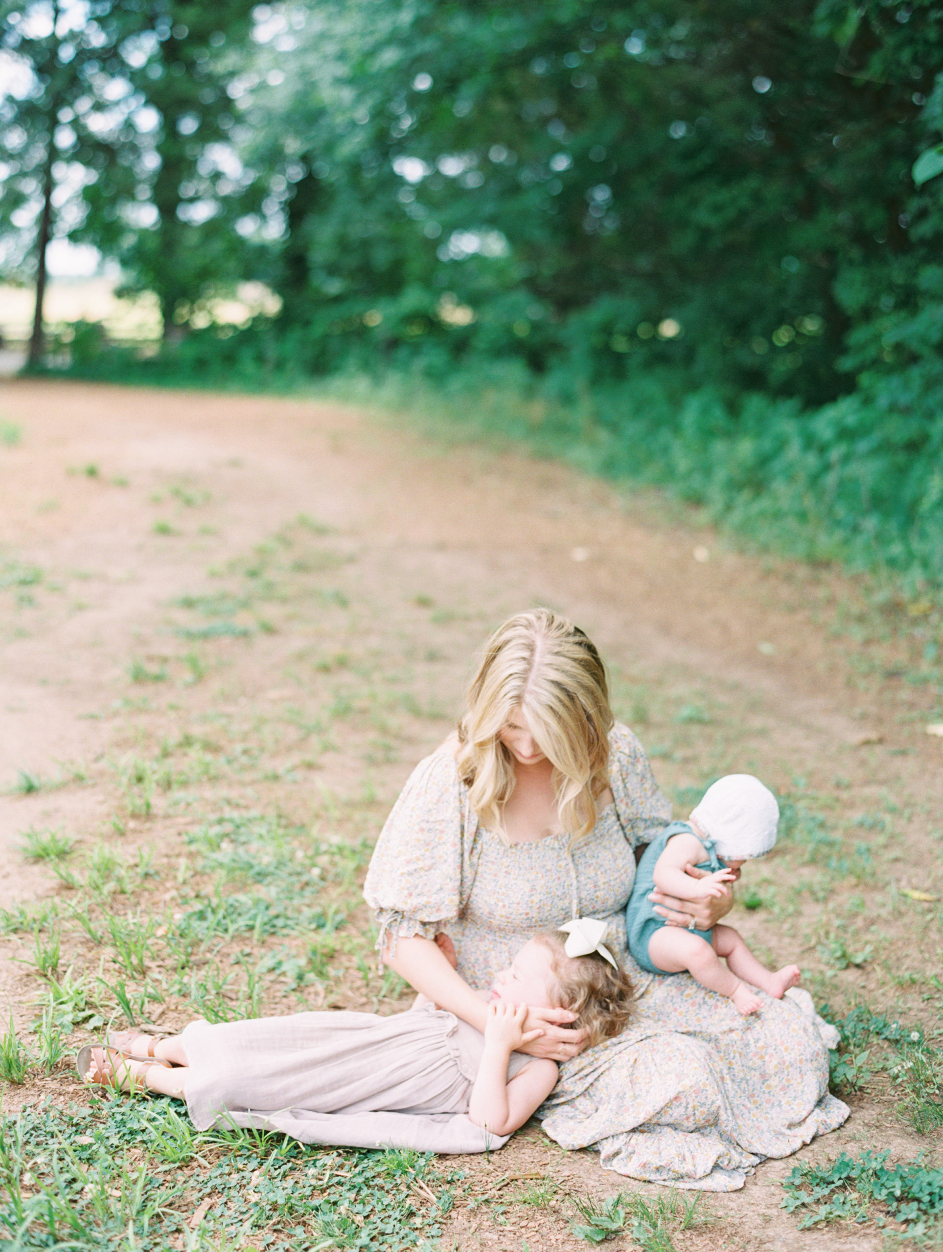 Mother sits on the ground holding her two girls during Murfreesboro Mom + Me Session