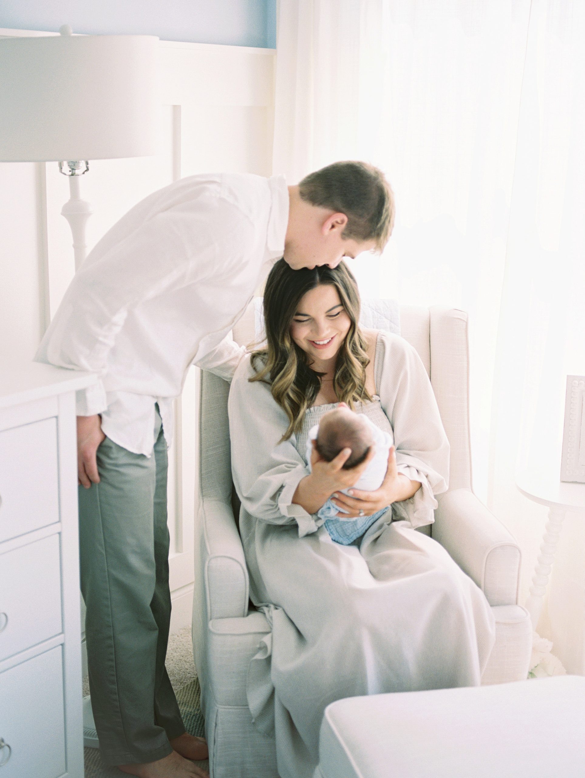New parents hold their son in nursery with backlighting during in-home session