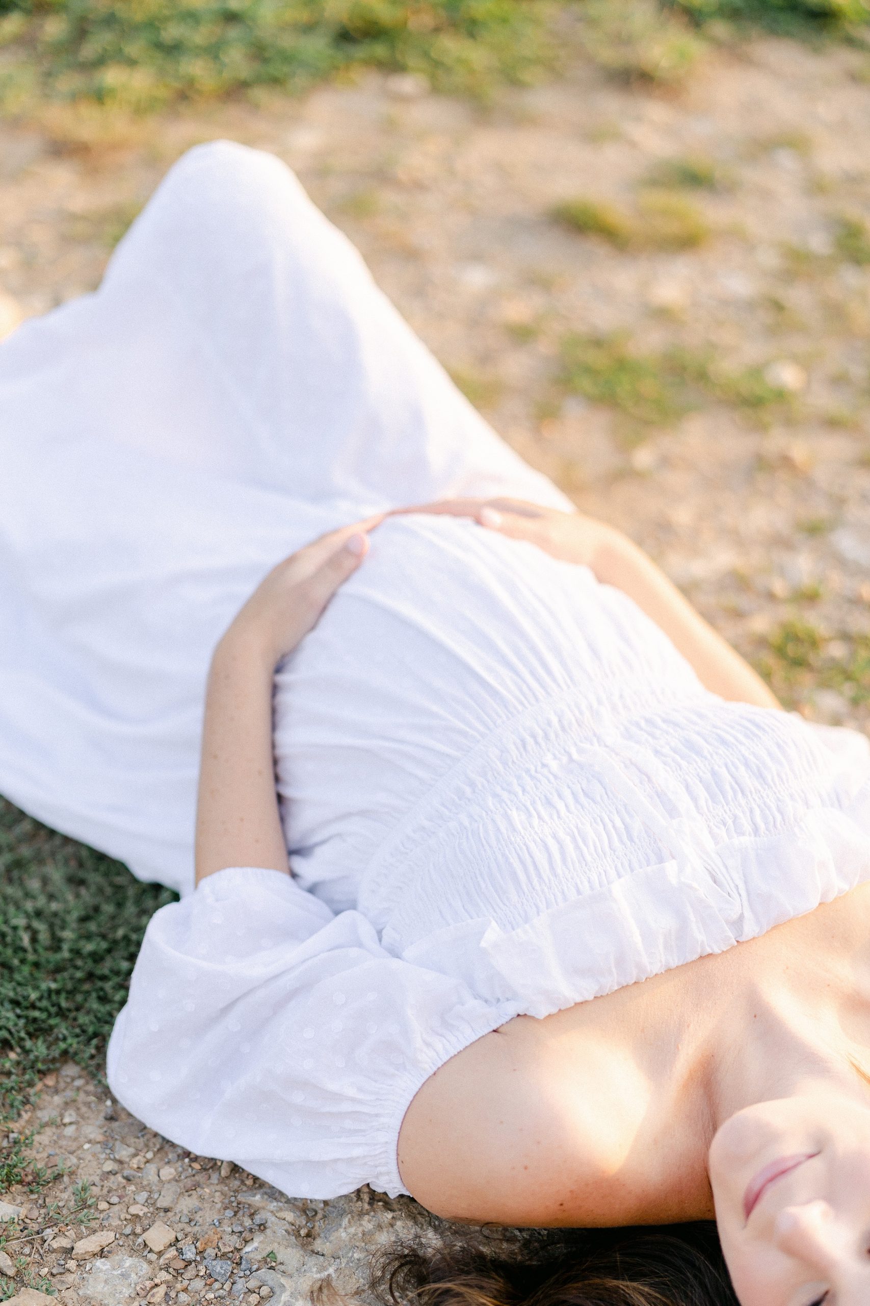 mom to be lays in green field during TN maternity session