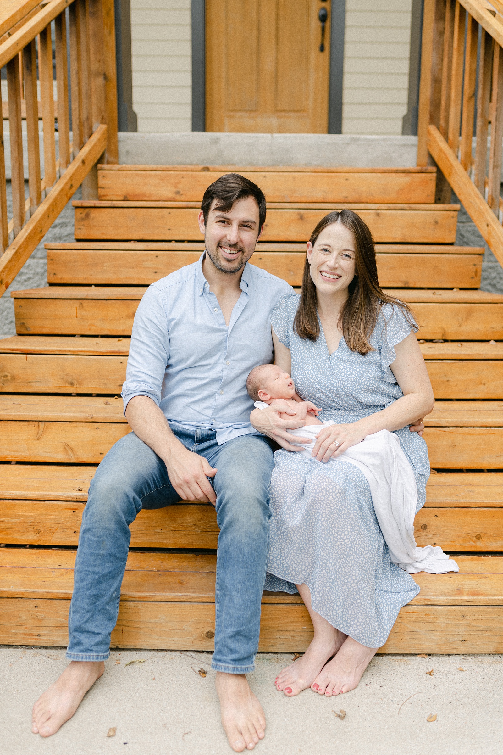 mom and dad sit on steps of Nashville home with newborn during Nashville Lifestyle Newborn Session captured by Grace Paul Photography