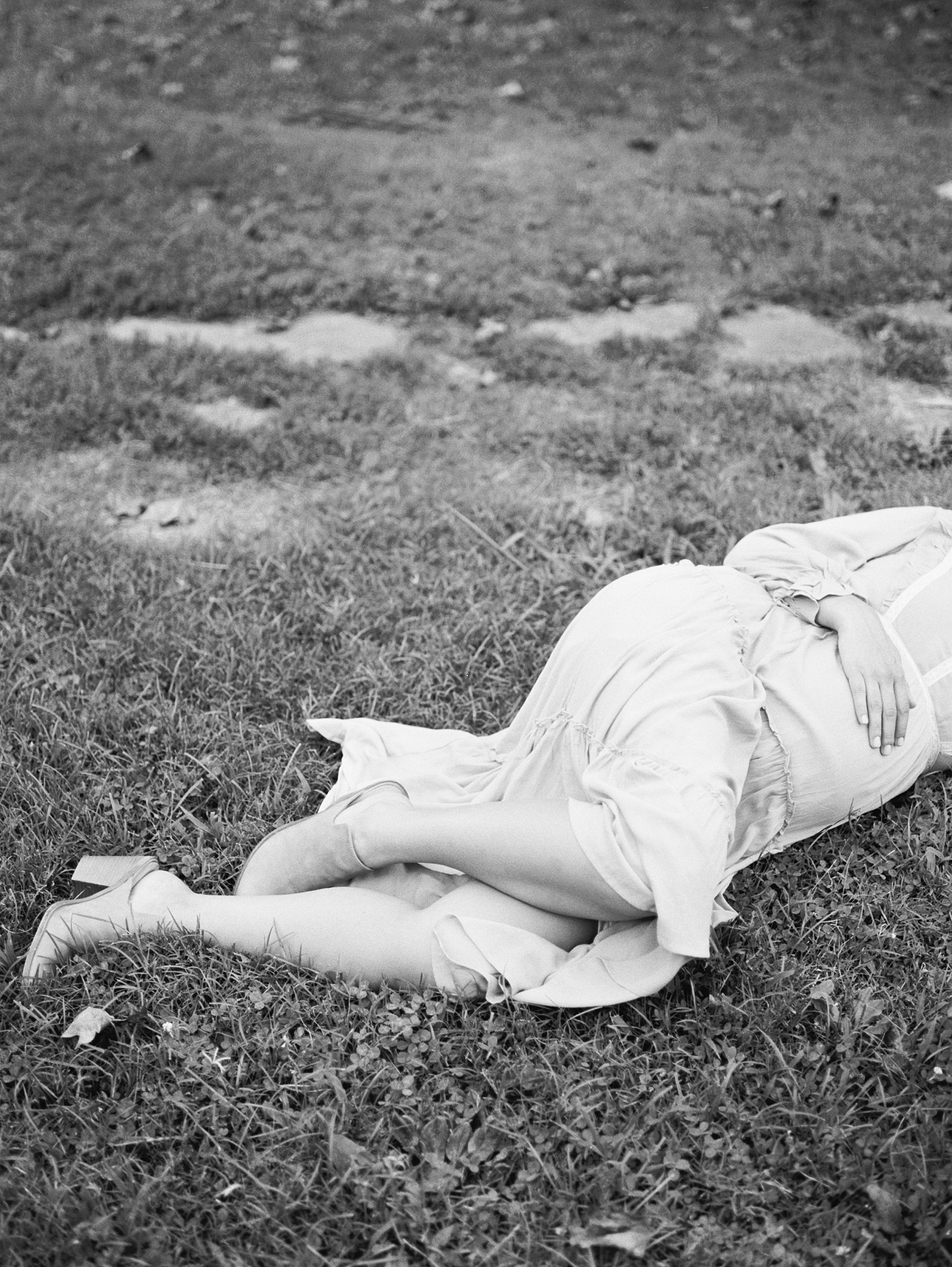 mom to be lays in grace holding belly during Nashville photo session