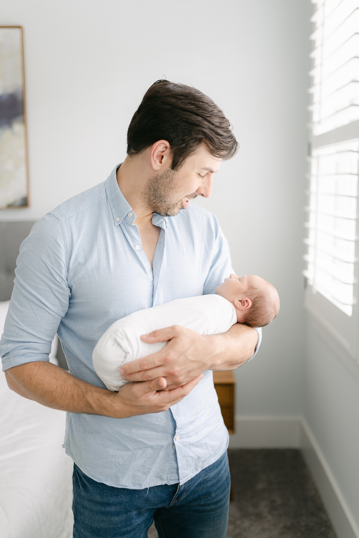 dad holding baby with head towards window-5 Tips for Taking Photos of Your Baby at home