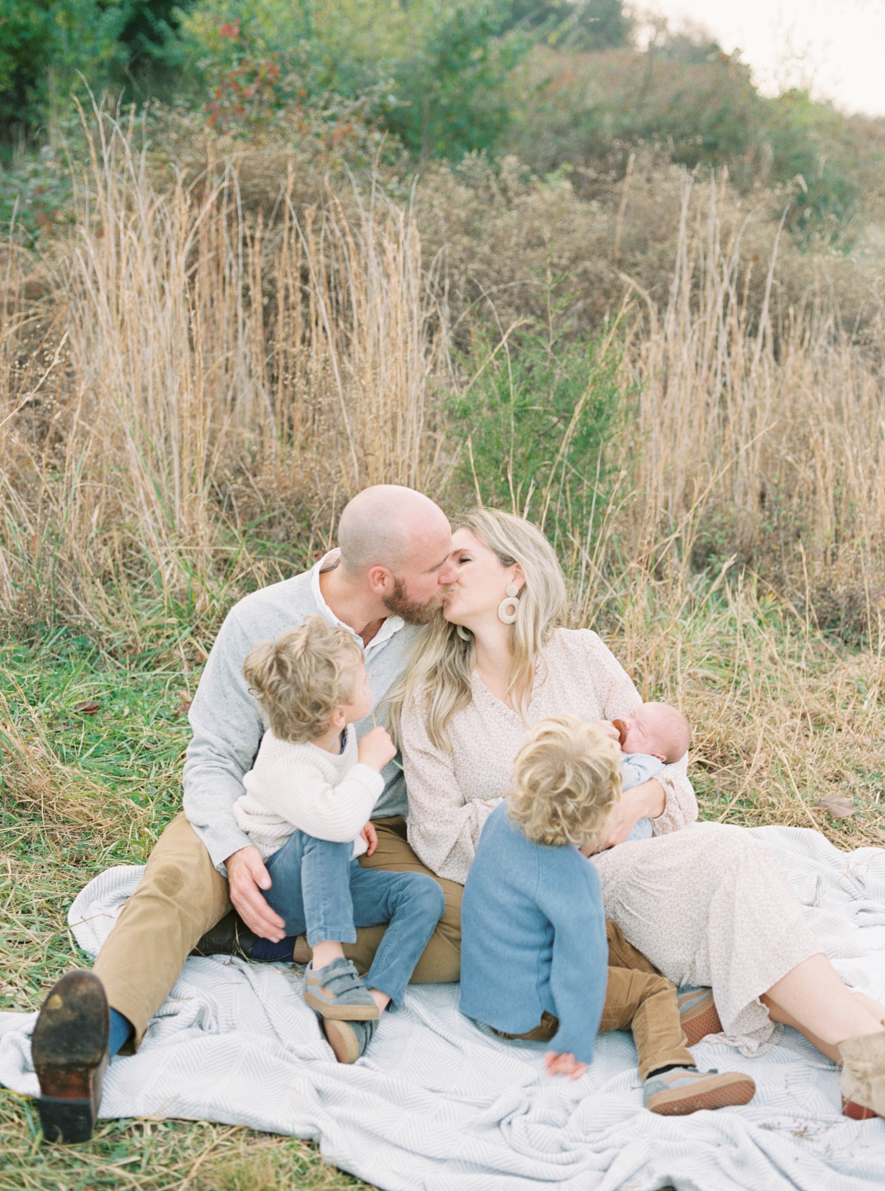 couple kiss surrounded by their 3 kids during Brentwood outdoor newborn and family session