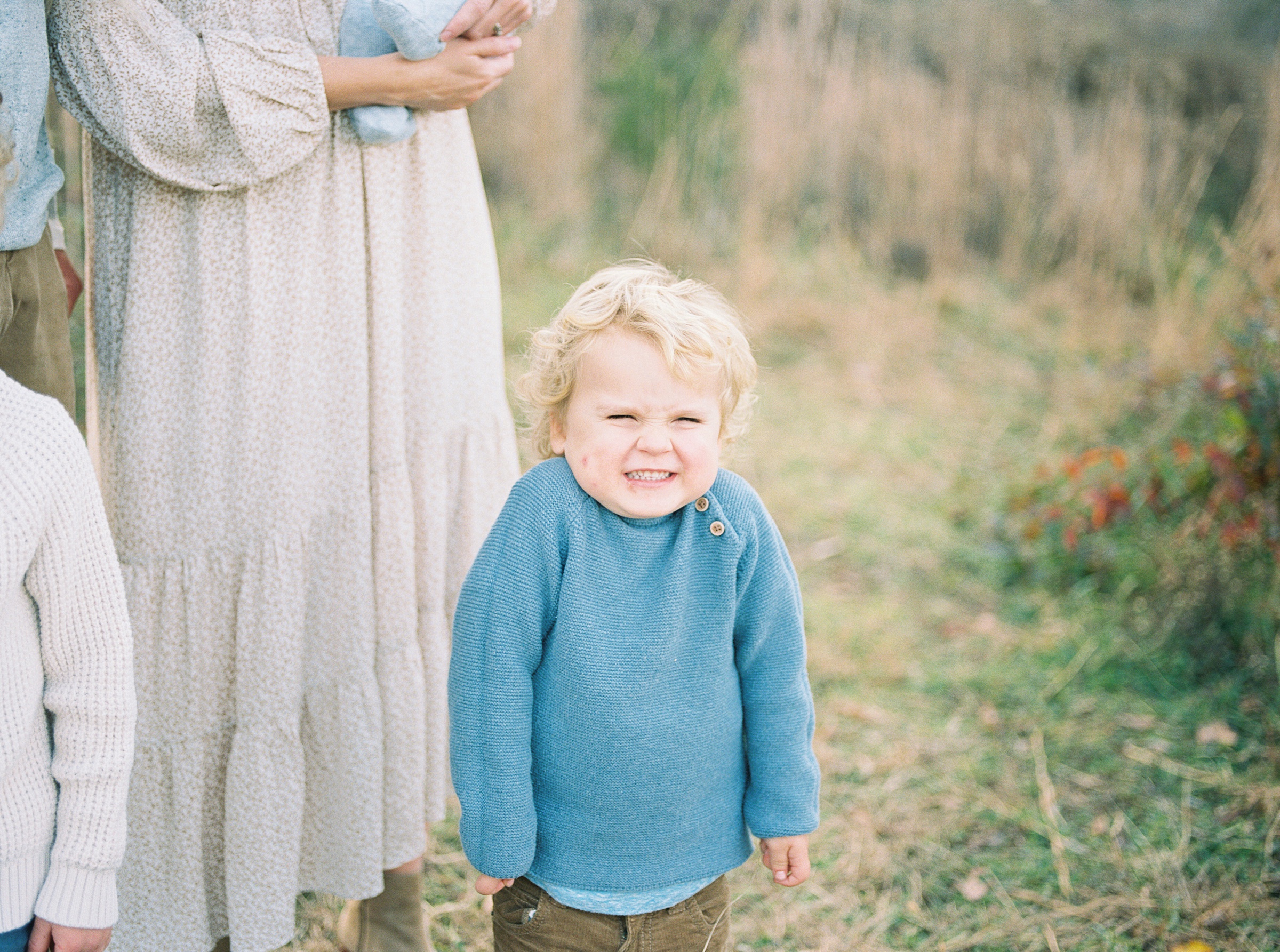 little boy in teal sweater smiles adorably for camera