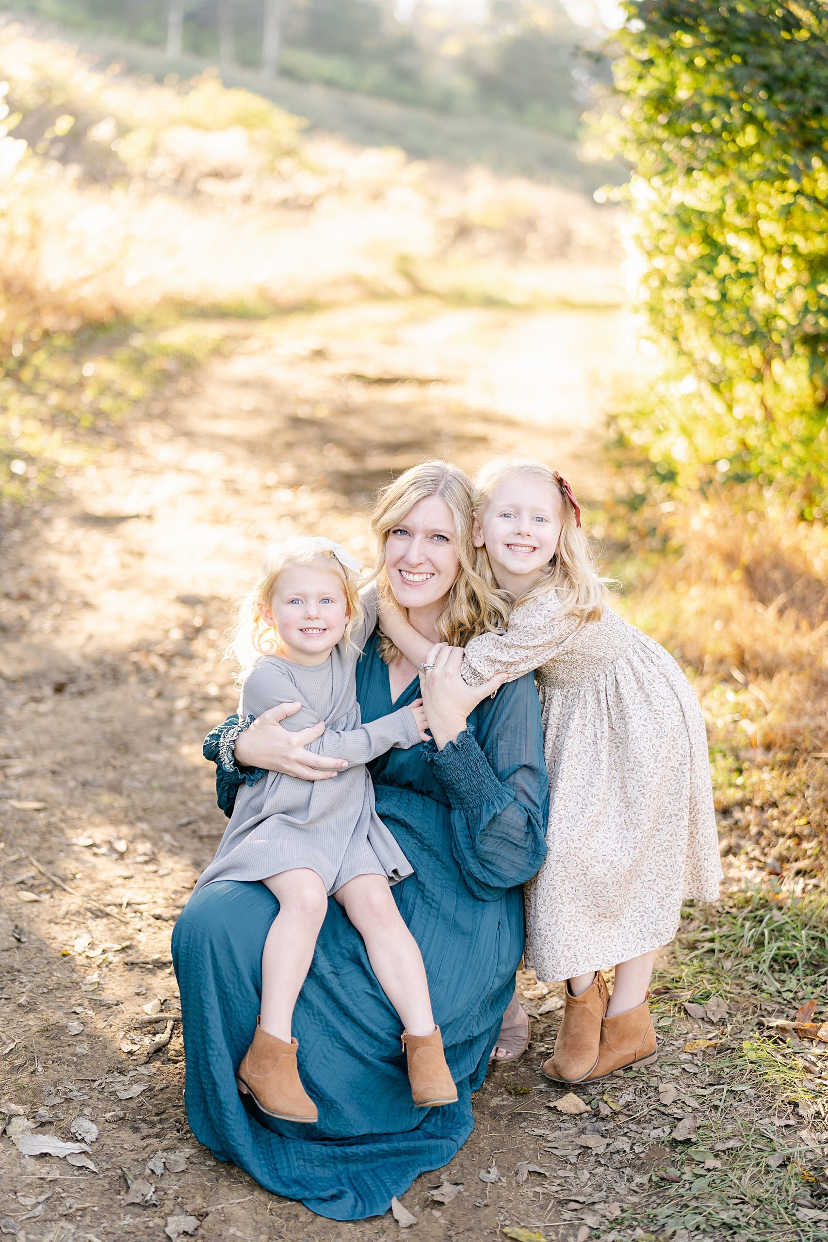 two little girls hug their mom in teal dress