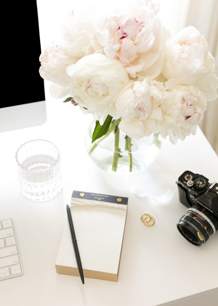 film camera sitting on desk with peonies