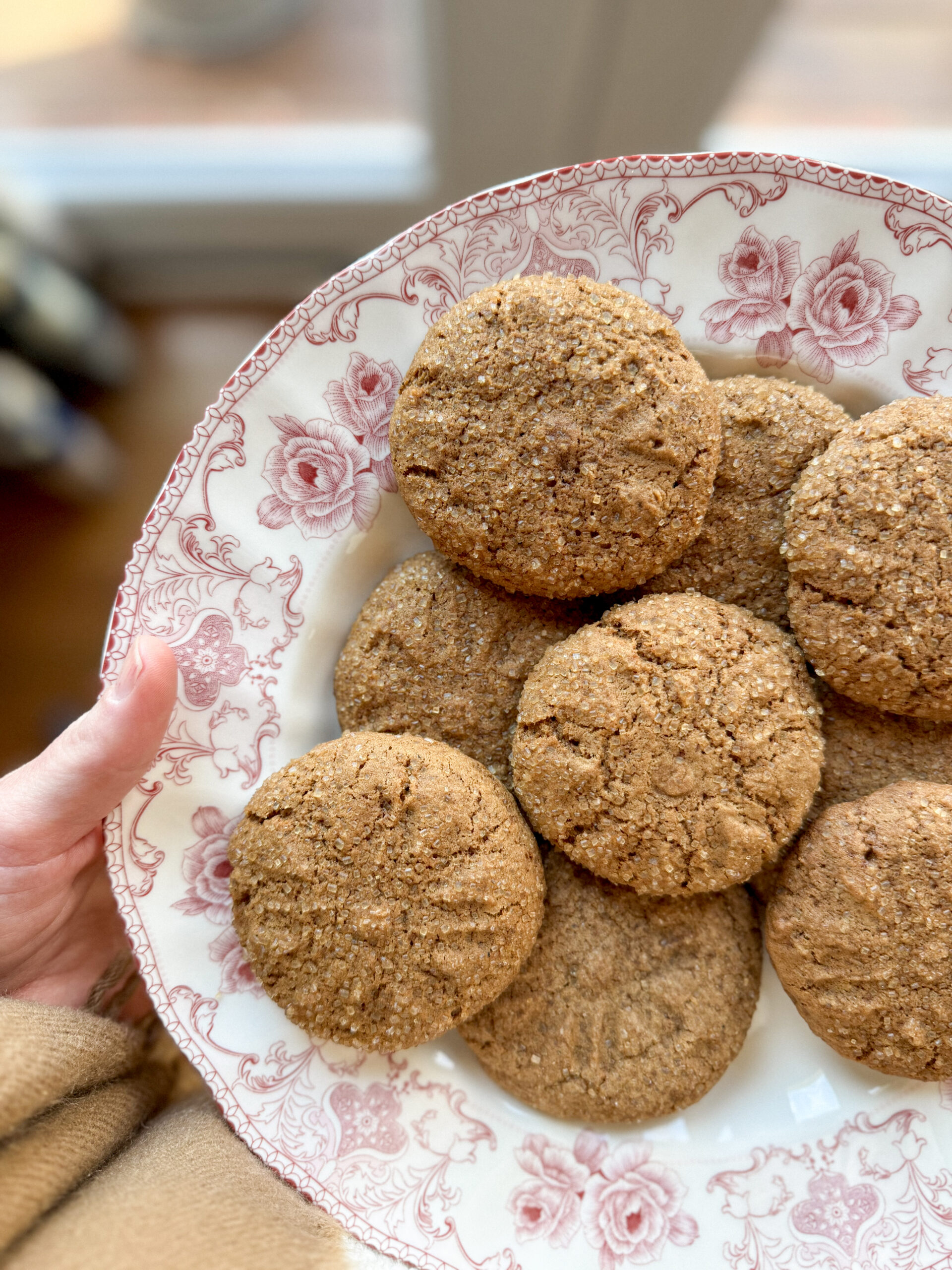 Gluten-free gingerbread cookies stacked on a plate with a cozy winter kitchen background